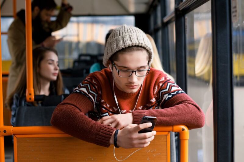 Un homme utilise son smartphone dans un bus