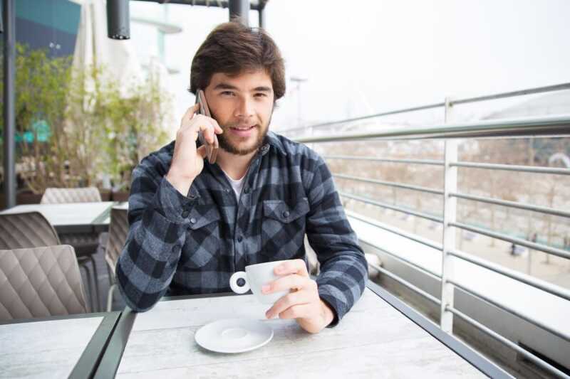Homme utilise son smartphone à la terrasse d'un café