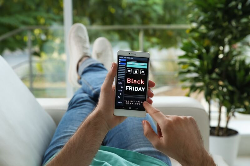 Un homme cherche un nouveau forfait sur son smartphone pendant le Black Friday