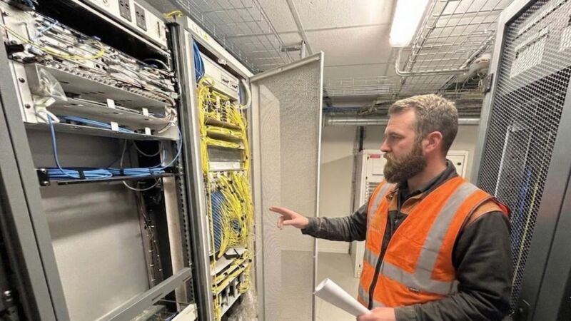 Un technicien intervient sur une armoire OLT dans un noeud de raccordement fibre (NRO)